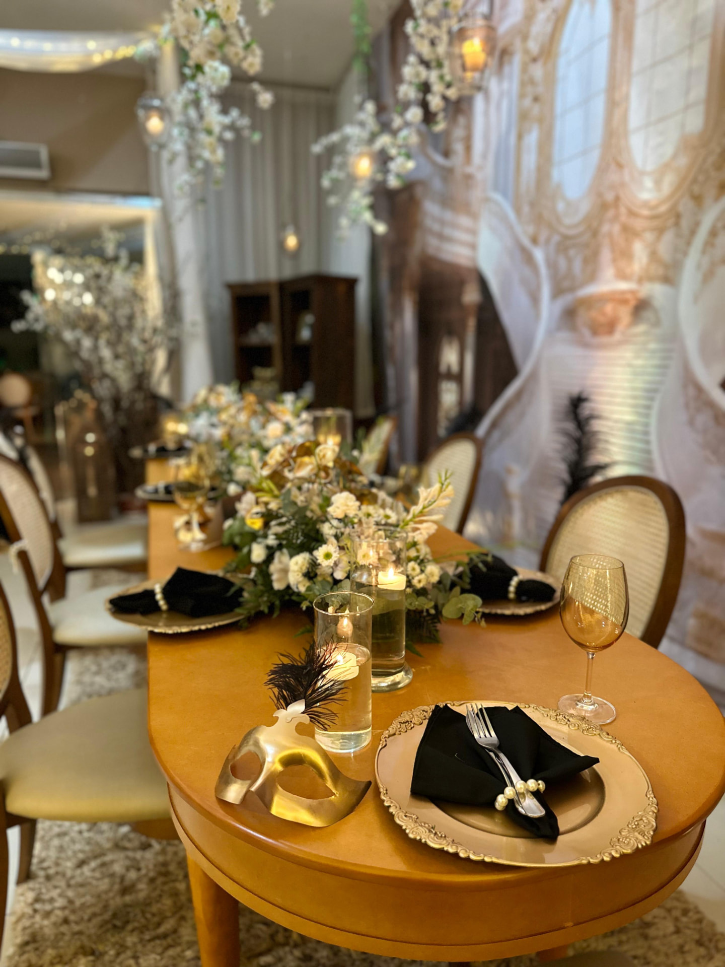 Mesa dos pais com arranjos florais, velas e louça dourada